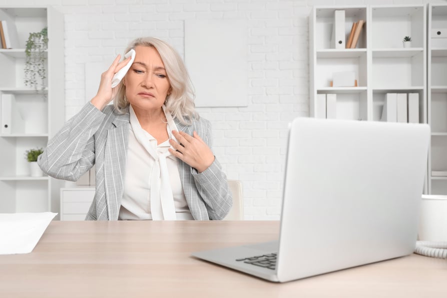 Mature Businesswoman Suffering from Hot Flashes in Office. Menopause Concept